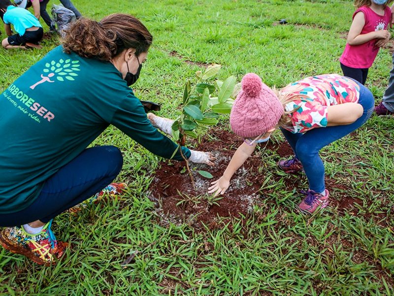 Uma mulher e uma criança plantando uma árvore