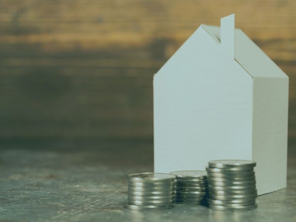 casinha de papel com moedas na frente representando a tributação em imoveis