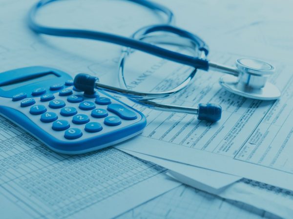 calculadora e estestoscópio em cima de uma mesa de papeis