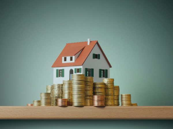 miniatura de uma casa com moedas na frente