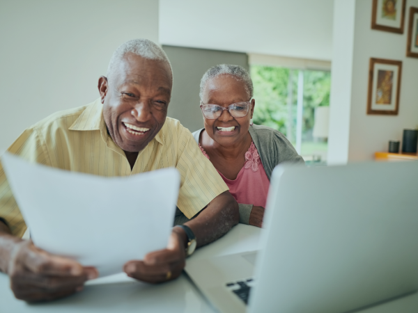 casal de idosos negroas sorrindo com documento em mãos
