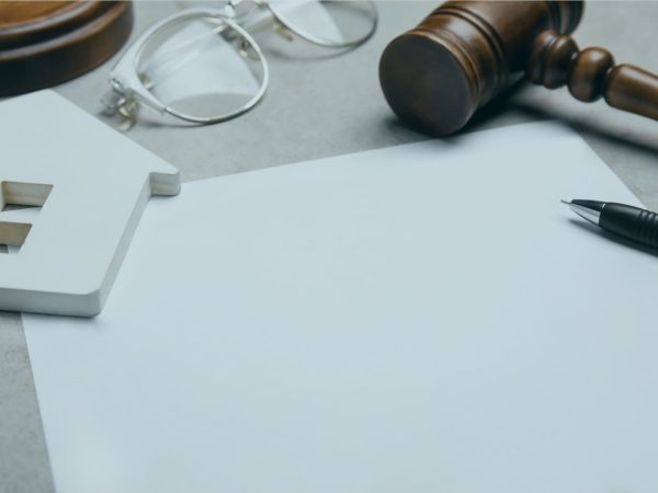 papel na mesa com martelo juridico e casa